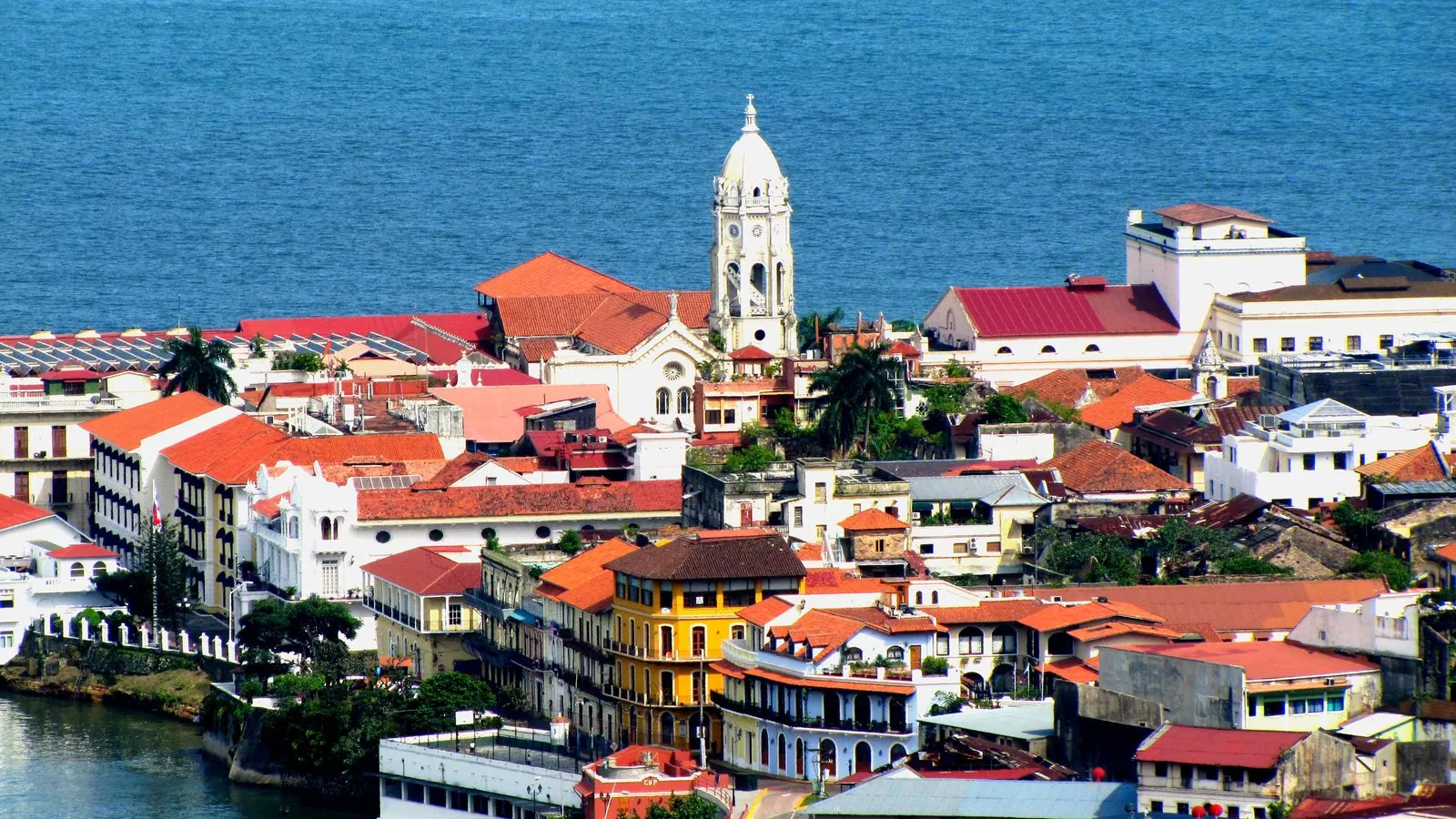 Orașul vechi din Panama City văzut de sus: acoperișuri cu țiglă roșie, case coloniale și clopotnița albă a unei biserici în fața Pacificului albastru.