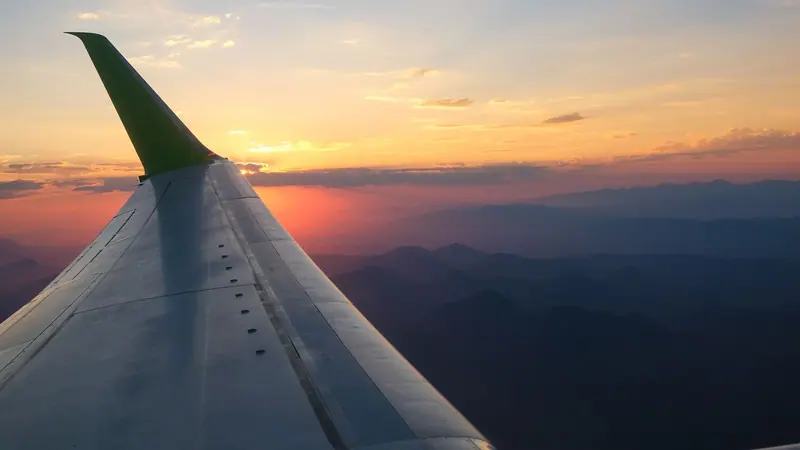 Tragfläche eines Flugzeugs über den Wolken zur goldenen Stunde